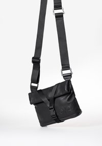 Black leather crossbody bag featuring an adjustable strap, snap closure, and embossed detailing on the front; smooth texture throughout.