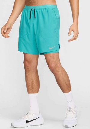 Turkoosit Nike-juoksushortsit, joissa on kiristysnauha vyötäröllä, kaksi etutaskua ja vasemmalla puolella heijastava logo. Sileä kangaspinta.