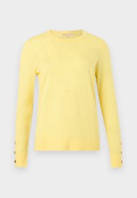 Pull jaune pâle à manches longues avec col rond et trois boutons marron sur chaque manchette, présenté sur un fond gris clair.