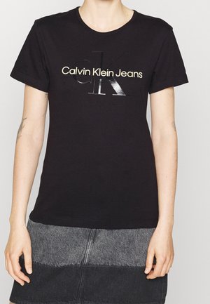 Czarna bawełniana koszulka z błyszczącym szarym logo "Calvin Klein Jeans", okrągłym dekoltem i krótkimi rękawami.