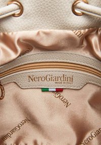 Interno in pelle color tan con texture satinata, dotato di una tasca con zip dorata e un'etichetta con la scritta "NeroGiardini MADE IN ITALY" con una bandiera tricolore.