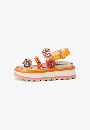 Sandale à plateforme avec des brides orange, décorée de pierres rondes colorées et de clous, et une semelle blanche avec des rayures roses et orange.