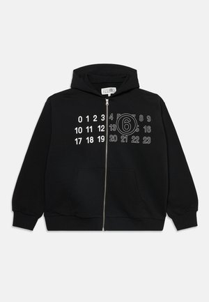 Sweat à capuche noir zippé avec des chiffres blancs imprimés sur la poitrine ; le chiffre 6 est entouré du côté droit. Aucune personne présente.