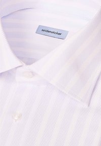 Chemise blanche à col pointu avec un motif subtil à rayures diagonales, montrant une étiquette cousue avec le nom de la marque "seidensticker."