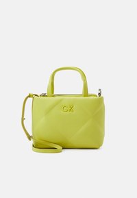 Prošívaná žlutá taška s horním uchycením a nastavitelným ramenním popruhem. Má zapínání na zip a vyražené logo "CK" na přední straně.