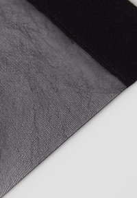 Transparent svart tyg med en texturerad yta och en solid svart kant. Lätt och flexibel, lämplig för lager eller drapering.