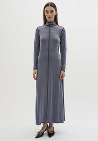 Langes, tailliertes Kleid aus gedämpftem grauen Stoff mit hohem Kragen und schwarzem Besatz entlang der Vorderseite, ausgestattet mit langen Ärmeln und einem geraden Saum.