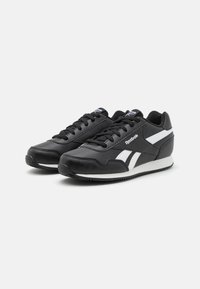 Scarpe sportive nere con tomaia in pelle liscia, dettagli bianchi, design con lacci e suola in gomma textured. Logo Reebok di lato.