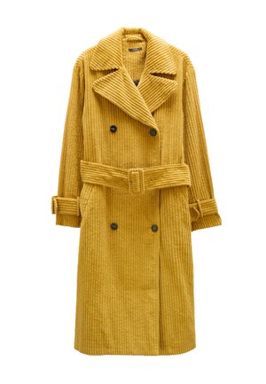 Musztardowo-żółty, prążkowany kordowy płaszcz dwurzędowy z paskiem w talii, dużymi klapami i zapiętymi mankietami. Posiada dwie przednie kieszenie.