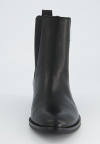 Bottines en cuir noir avec une texture lisse, des panneaux latéraux en élasthanne et une semelle en caoutchouc robuste, dotées d'une languette à l'arrière.