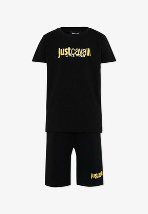 Set composto da t-shirt nera a maniche corte e pantaloncini con testo giallo "Just Cavalli Little Rogue" sul petto e sulla parte inferiore della gamba sinistra.