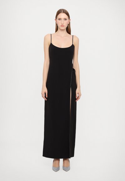 Rochie maxi neagră fără mâneci, cu bust bine croit, fante laterale și țesătură netedă. Purtați cu pantofi cu toc înalt argintii. Design simplu și elegant.