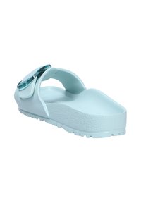 Sandalia de color azul claro que presenta una plantilla texturizada, una correa flexible con una hebilla circular transparente y una suela gruesa y duradera con protuberancias para tracción.