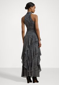 Rankovėmis neslėgta, juoda ir balta paisley raštuota suknelė su sluoksniuotais raukšlėmis ir aukštu kaklu. Dėvima su juodomis aukštakulnėmis botais.