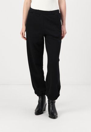 Black jogger pants with elastic waistband and cuffs, featuring side pockets and a subtle logo detail on the front. Made from soft, stretchy fabric.
