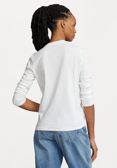 Weißes Langarmshirt aus Baumwolle, mit rundem Halsausschnitt und taillierten Ärmeln. Die Rückseite zeigt eine glatte Textur und einen lässigen Schnitt.