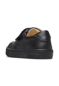 Sneaker per bambini in pelle nera con cinturino in velcro, collo imbottito e suola in gomma testurizzata, mostrata da dietro su uno sfondo bianco.