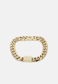 Pulsera de cadena de oro con eslabones pulidos, que presenta un audaz logo "BOSS" y un cierre rectangular. Textura suave con acabado brillante.
