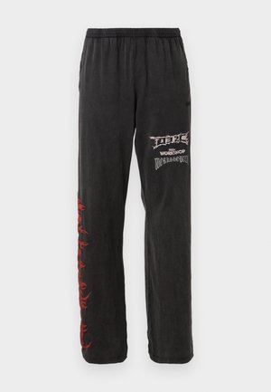 Black sweatpants with an elastic waistband and red graphic accents along the left leg. Features printed text in white on the right side.