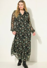 Lange zwarte chiffon jurk met bloemmotief in teal en bruin. Heeft een V-hals, lange mouwen en een geplooide taille.