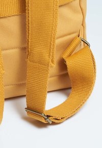 Borsa di cotone gialla con texture intrecciata e robusti manici in tessuto. Presenta un attacco in metallo sulla tracolla per garantire durata.