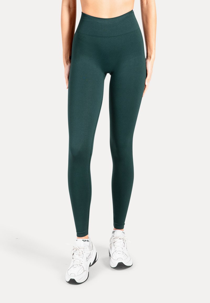 Leggings verde scuro a vita alta in tessuto liscio ed elastico. Presentano un design senza cuciture con una vestibilità aderente alla caviglia.