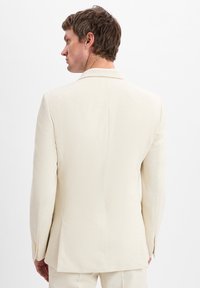 Cremfarbener Anzugjacke mit slim fit, glatter Textur und Reverskragen. Verfügt über einen einzelnen Rückenschlitz und dekorative Knöpfe.