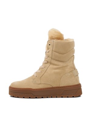 Beige suède hoge boots met een zachte voering van bont, een ronde neus, een vetersluiting aan de voorkant en een bruine rubberen zool met een gestructureerde grip.