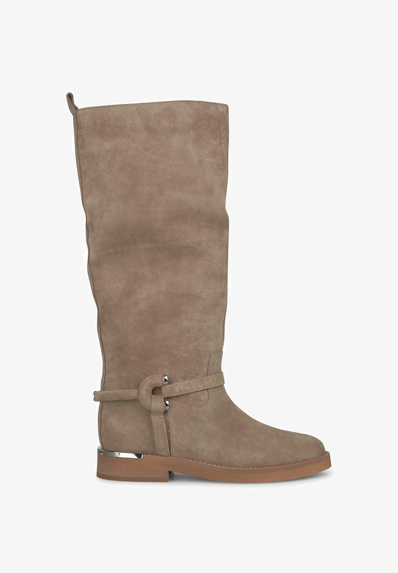 Bota alta de ante en color topo con punta redondeada, suela plana y detalles en metal plateado. Cuenta con una correa decorativa con un detalle en forma de lazo.