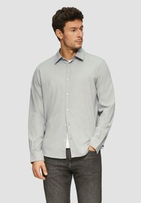 Hellgraues langärmliges Hemd mit Knopfdesign, weichem Material und dezentem Streifenmuster. Das Modell trägt es zu dunklen Jeans.