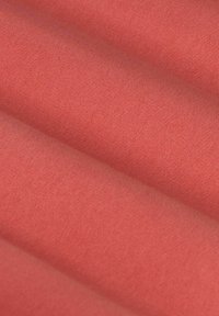 Koraalkleurige stof met een zachte textuur, gekenmerkt door gladde, gelijkmatige plooien en een consistente patroon op het oppervlak. Ideaal voor verschillende textieltoepassingen.