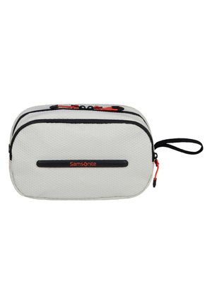 Samsonite travel pouch in textured white fabric, featuring two zippers with black trim and red accents, plus a side handle for easy carrying.