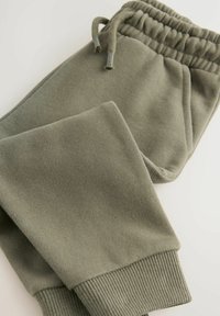 Pantalons de survêtement vert olive avec taille élastique, cordon de serrage, poches latérales et poignets côtelés, étalés à plat sur un fond blanc.