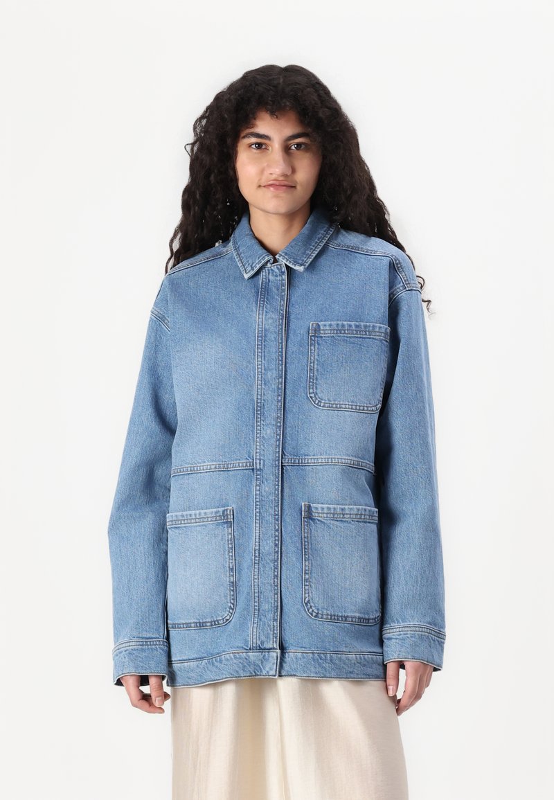 Denimjakke i lys blå med krage, fire frontlommer, lange ermer og avslappet passform. Glatt tekstur og uformelt design.