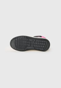 Semelle de chaussure noire avec un motif de semelle texturé. Présente des accents roses sur le côté et un design lisse et courbé. Matériau durable.