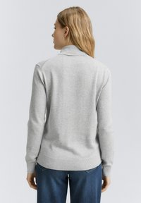 Grå polotröja med ribbad krage, långa ärmar och ribbat nederkant. Tyget verkar slätt och mjukt, designat utan mönster eller detaljer.