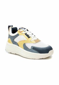 Le sneakers presentano un mix di rete bianca, un pannello giallo con texture a serpente, accenti blu navy e una spessa suola bianca con scanalature orizzontali.