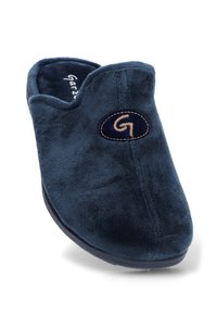 Zapatilla de terciopelo azul marino con una textura suave, forma redondeada y un parche de logo cosido. Diseño de espalda abierta para un fácil acceso al pie.