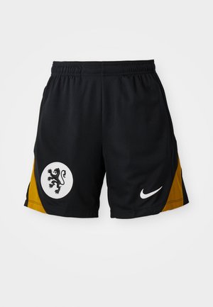 Pantalones cortos deportivos negros con un panel de acento amarillo, un emblema circular blanco con un león negro y un logo de Nike blanco en el dobladillo.