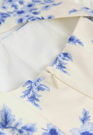 Bloemenpatroon jurk met blauwe ontwerpen op een crèmekleurige achtergrond. Voorzien van een ritsluiting en een gladde, geweven textuur.