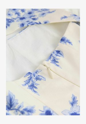Floral-patterned dress with blue designs on a cream background. Features a zipper closure and a smooth, woven texture.