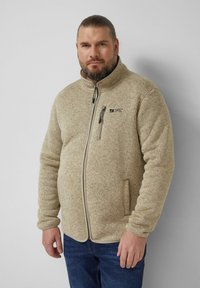 Veste en polaire beige avec fermeture éclair à l'avant, col montant, deux poches latérales et un écusson logo sur la poitrine. Texture douce avec un motif chiné.