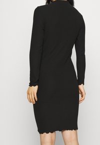 Černé pruhované midi šaty s dlouhými rukávy, krajkovými manžetami a lemem. Přiléhavý střih, vyrobené z měkkého, pružného materiálu.