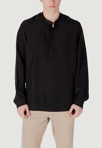 Camicia nera a maniche lunghe con placket abbottonato e colletto rialzato. Presenta una texture liscia, realizzata in tessuto leggero, aderente ai polsi.