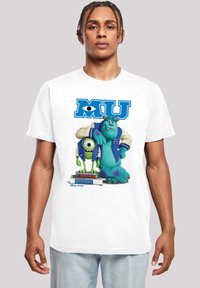 White t-shirt featuring cartoon characters Mike and Sulley from Monsters University, with blue varsity jackets and stacked books underneath.