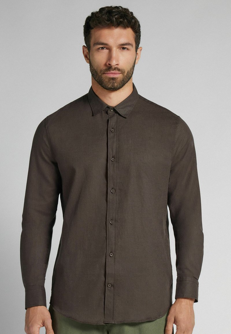 Bruine lange mouwen shirt met een button-down kraag, gemaakt van textuurstof. Heeft knopen aan de voorkant en een zoom die aan de zijkanten omhoog krult.