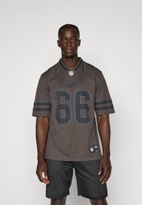 Tamno sivi NFL dres s brojem 66, kratkim rukavima sa prugama i okruglim dekolteom. Nosi se preko crnih mrežastih kratkih hlača.