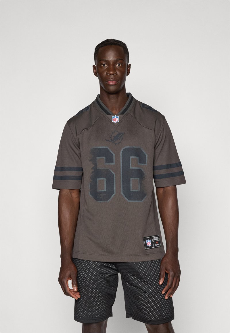 Tamno sivi NFL dres s brojem 66, kratkim rukavima sa prugama i okruglim dekolteom. Nosi se preko crnih mrežastih kratkih hlača.