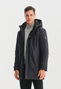 Czarna kurtka ocieplana z kapturem, przednimi kieszeniami i mankietami na napy. Charakteryzuje się gładką fakturą materiału oraz logo na rękawie.