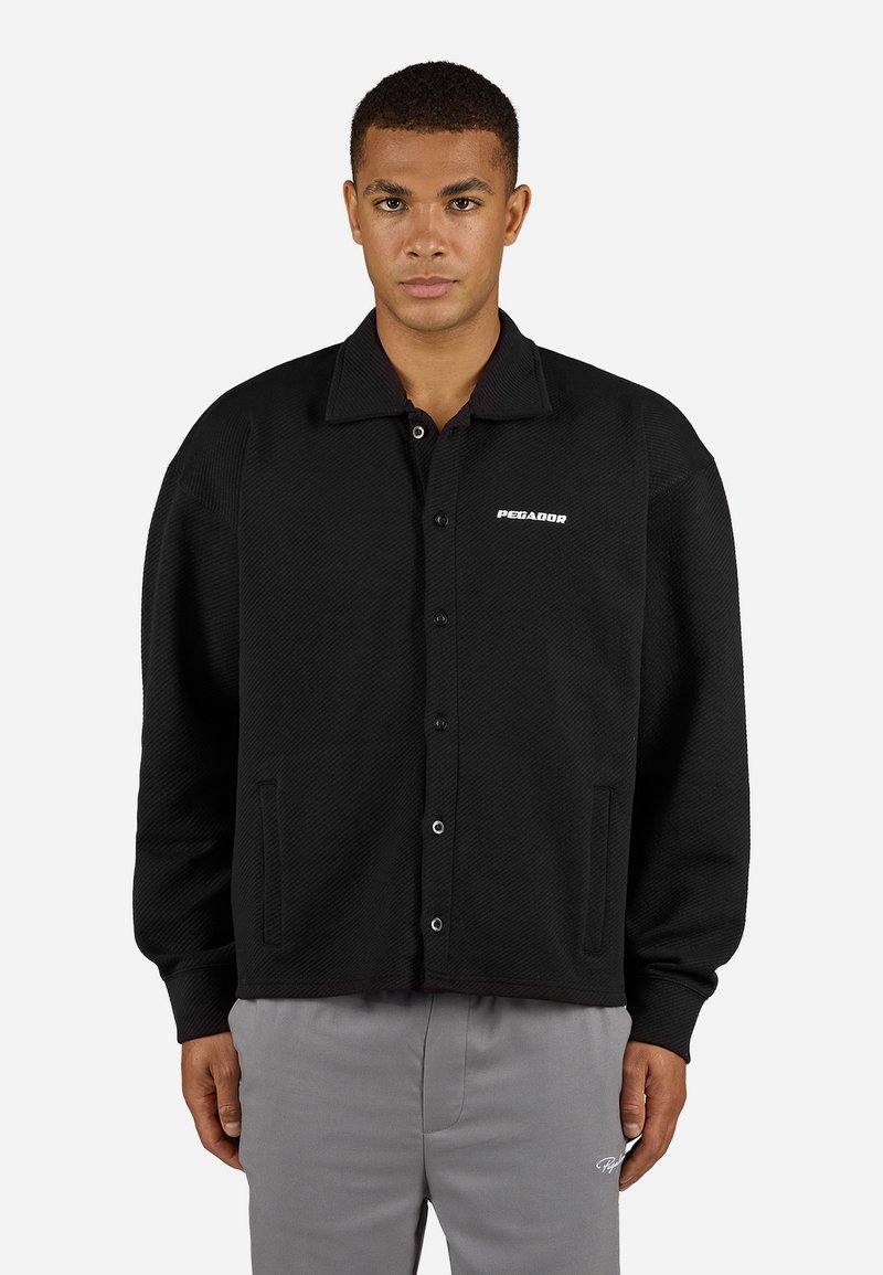 Black button-up jacket with a textured pattern, a flat collar, and two side pockets. Features a white logo on the left chest area.